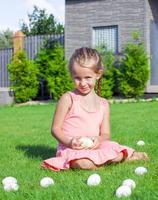 ritratto di poco adorabile ragazza giocando con bianca Pasqua uova nel il cortile foto