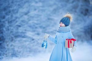 adorabile ragazza con lampada e Natale scatola regalo nel inverno su natale vigilia all'aperto foto