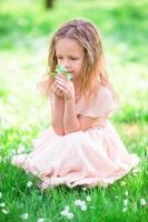 adorabile poco ragazza godendo odore nel un' fioritura primavera giardino foto
