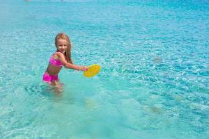 poco ragazza giocando frisbee durante tropicale vacanza nel il mare foto