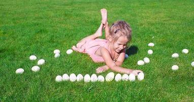 poco contento ragazza giocando con Pasqua uova su verde erba foto