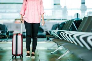 avvicinamento aereo passeggeri con passaporti e imbarco passaggio e rosa Bagaglio nel un aeroporto sala. giovane donna nel internazionale aeroporto a piedi con sua bagaglio. foto