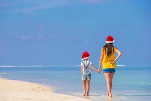 poco ragazza e giovane madre nel Santa cappelli durante spiaggia vacanza foto