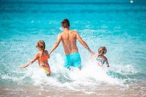 poco ragazze e contento papà avendo divertimento durante spiaggia vacanza foto