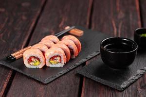 Sushi rotolo maguro con tonno, affumicato anguilla, avocado e tobiko su nero tavola avvicinamento. Sushi menù. giapponese cibo. foto