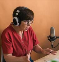 ritratto di maturo donna indossare cuffie e parlando a in linea Radio stazione - Podcast e trasmissione concetto foto