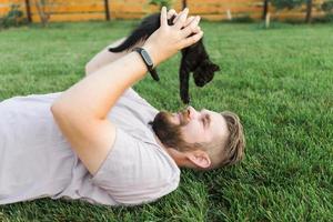 uomo con poco gattino dire bugie e giocando su erba - amicizia amore animali e animale domestico proprietario concetto foto