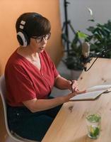 ritratto di maturo donna indossare cuffie e parlando a in linea Radio stazione - Podcast e trasmissione concetto foto