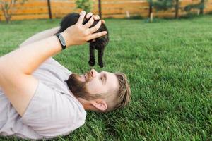 uomo con poco gattino dire bugie e giocando su erba - amicizia amore animali e animale domestico proprietario concetto foto