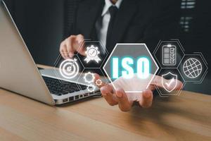 iso standard qualità controllo concetto, persona mano Tenere iso icona su virtuale schermo su scrivania posto di lavoro, garanzia garanzia, attività commerciale tecnologia concetto. foto