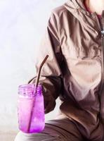 persona in possesso di un bicchiere viola mentre è seduto foto