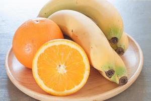 primo piano di una ciotola di frutta con arance e banane foto