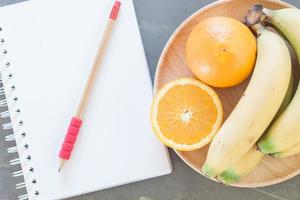 taccuino e matita accanto a una ciotola di frutta foto