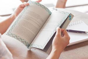 primo piano delle mani che tengono un libro in un caffè foto