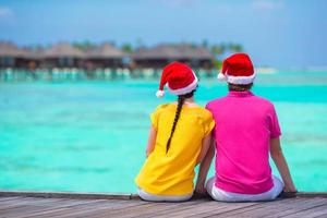 giovane coppia nel Santa cappelli rilassante su spiaggia durante Natale vacanza foto