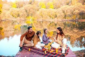 contento famiglia su un' picnic nel il parco a autunno foto