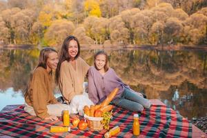 contento famiglia su un' picnic nel il parco a autunno foto