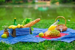 cestino da picnic con frutta, pane e bottiglia di vino bianco foto