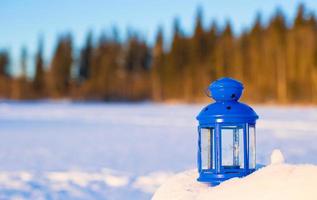 blu lanterna con un' candela su bianca neve all'aperto foto