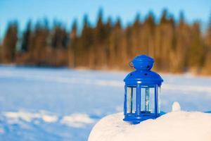 blu lanterna con un' candela su bianca neve all'aperto foto