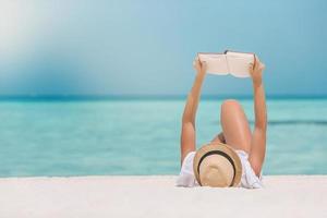 giovane donna lettura libro durante tropicale bianca spiaggia foto