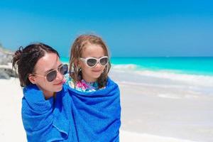 contento madre e poco ragazza su il spiaggia vacanza. famiglia nel asciugamano su il riva del mare foto