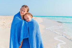 adorabile poco ragazze insieme avvolto nel asciugamano a tropicale spiaggia foto