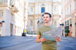 uomo turista con un' città carta geografica nel Europa strada. caucasico ragazzo guardare con carta geografica di europeo città. foto