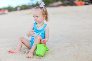 poco ragazza a tropicale bianca spiaggia fabbricazione sabbia castello foto