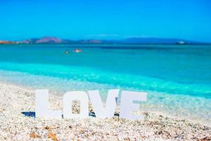 parola amore su tropicale spiaggia sfondo di il turchese mare e blu cielo foto