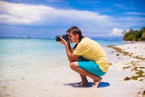 giovane che scatta foto su una spiaggia tropicale