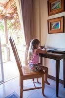 carino poco ragazza con tavoletta computer in casa foto