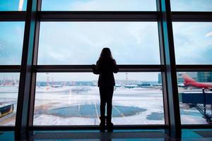 poco ragazza nel aeroporto vicino grande finestra mentre aspettare per imbarco foto