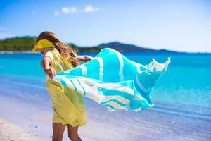 poco ragazza avere divertimento con spiaggia asciugamano durante tropicale vacanza foto