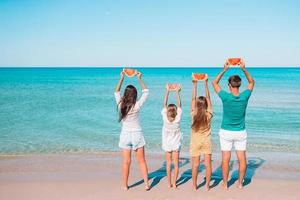 contento famiglia mangiare anguria su il spiaggia. foto