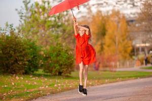 contento bambino ragazza ride sotto rosso ombrello foto
