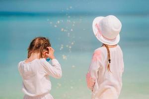 adorabile poco ragazze avere divertimento insieme su bianca tropicale spiaggia foto