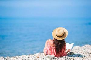 giovane donna lettura libro durante tropicale bianca spiaggia foto