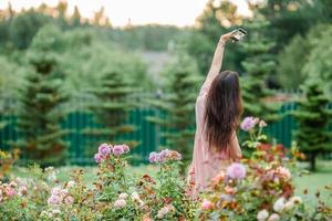 giovane ragazza nel un' fiore giardino tra bellissimo Rose. odore di Rose foto