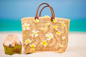 avvicinamento bellissimo Borsa con frangipani fiori e Noce di cocco su bianca spiaggia foto