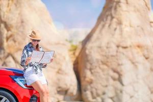 donna strada inciampare e guardare a il carta geografica. viaggio di auto foto