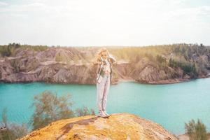 bellissimo ragazza su il superiore di il roccia con blu lago su sfondo foto