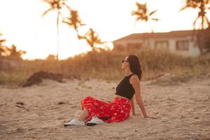 contento donna godendo bellissimo tramonto su il spiaggia foto