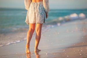 femmina gambe su il spiaggia avvicinamento. donna nel vestito a piedi su il spiaggia foto