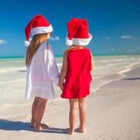 poco carino ragazze nel Natale cappelli su il esotico spiaggia foto