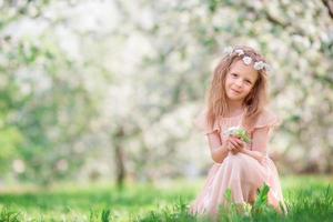 poco ragazza nel fioritura ciliegia albero giardino all'aperto foto