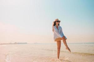 donna posa su il spiaggia godendo estate vacanze guardare a il mare foto