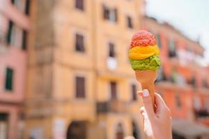 gustoso dolce gelato avvicinamento nel mani sfondo vecchio italiano villaggio foto