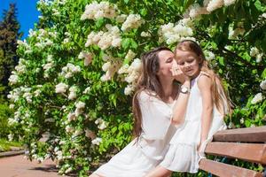 contento madre e adorabile ragazza godendo caldo giorno nel lussureggiante giardino foto