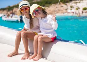 ritratto di poco carino ragazze godendo andare in barca su barca nel il Aperto mare foto